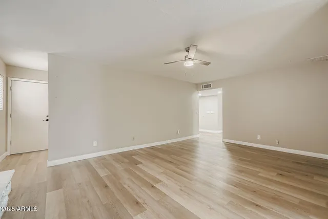 an empty room with wooden floor and ceiling fan