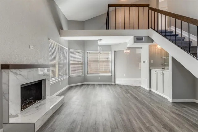 a view of an empty room with wooden floor fireplace and a window