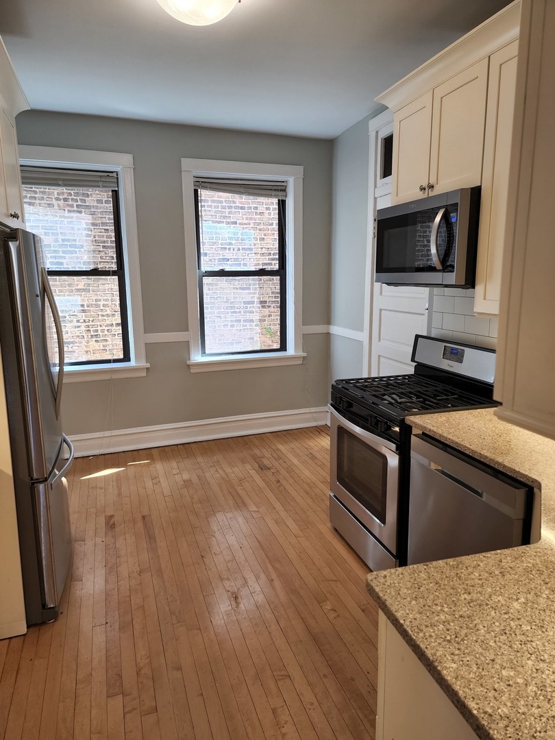 5225 North Clark Street, Unit 2 Chicago, IL 60640 - Photo 7 of 21 a kitchen with granite countertop a stove and a microwave