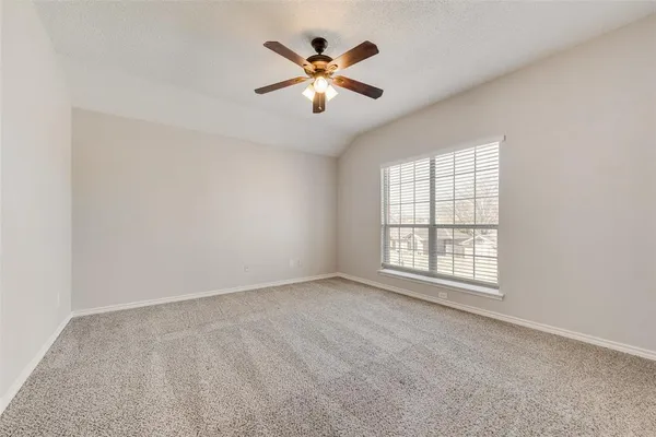 an empty room with ceiling fan and windows