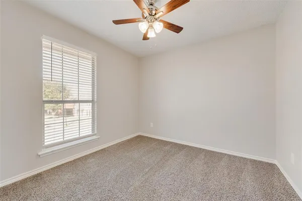 an empty room with a window and a fan