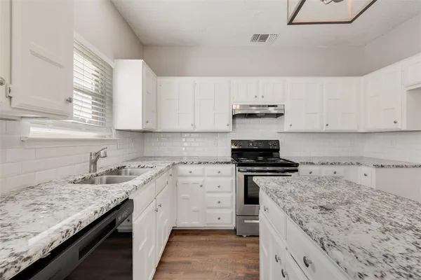 a kitchen with granite countertop a sink stove and cabinets