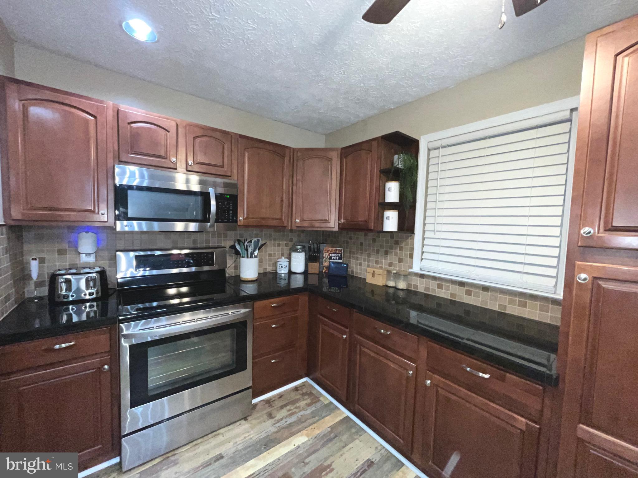 103 Broad Leaf Court Rising Sun, MD 21911 - Photo 12 of 47 a kitchen with granite countertop wooden cabinets stainless steel appliances and a window