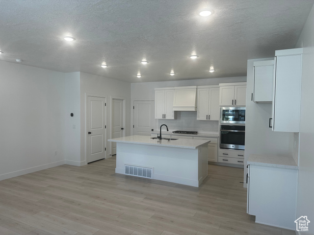 80 South Moonlit Road Mapleton, UT 84664 - Photo 4 of 18 Kitchen featuring stainless steel appliances, decorative backsplash, an island with sink, light stone countertops, and a textured ceiling