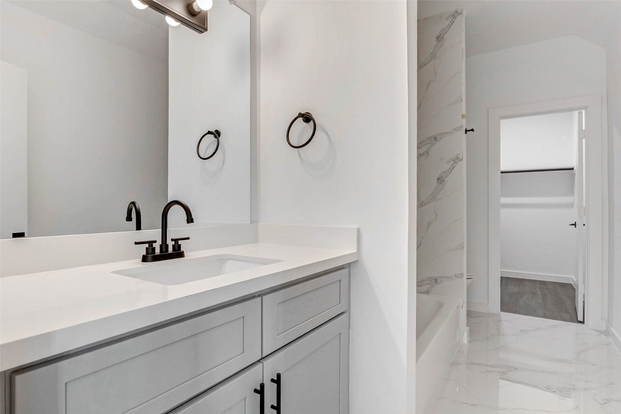 6017 Beall Street Houston, TX 77091 - Photo 27 of 33 This dual-sink ensuite bath features stone-look porcelain tile, custom cabinetry, and sleek black hardware. A deep soaking tub completes this spa-inspired retreat.