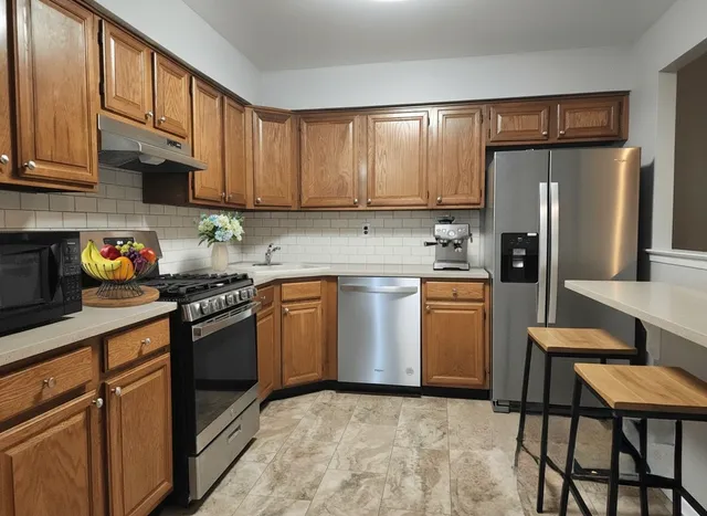 a kitchen with stainless steel appliances granite countertop a refrigerator sink and stove