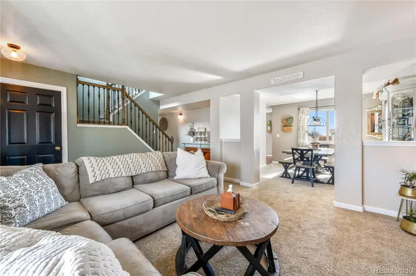 a living room with furniture and a dining room with wooden floor