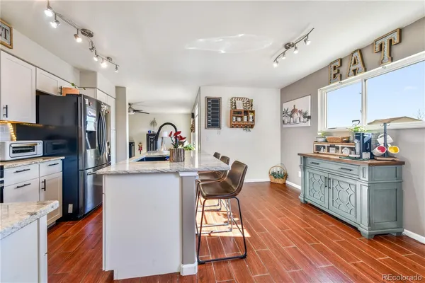 a kitchen with stainless steel appliances granite countertop a sink a stove a refrigerator cabinets and a dining table