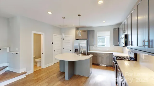 a large dining hall with stainless steel appliances granite countertop a sink dishwasher a dining table and chairs with wooden floor