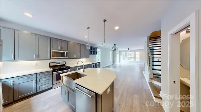 a kitchen with stainless steel appliances a stove a sink a microwave a refrigerator and cabinets