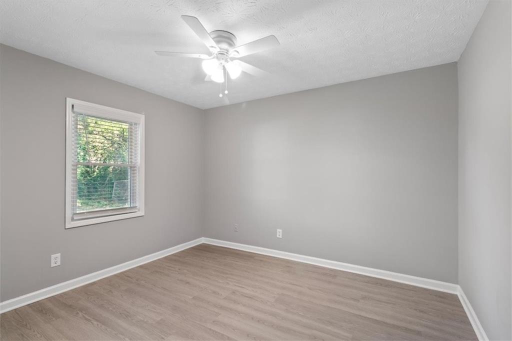 894 Five Forks Trickum Road Southwest Lawrenceville, GA 30046 - Photo 11 of 28 an empty room with wooden floor and windows