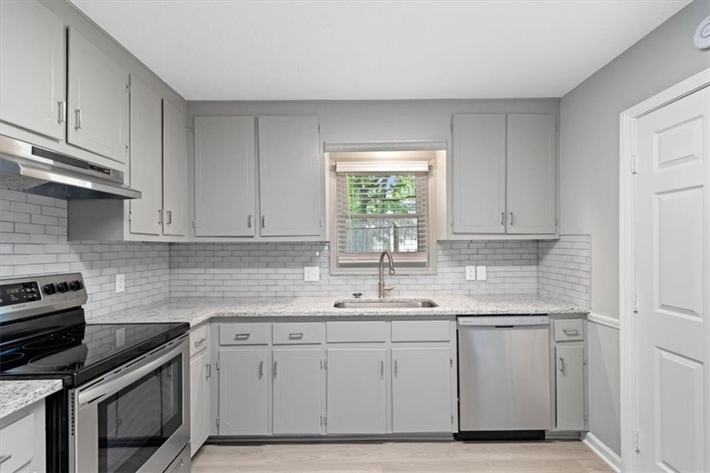 894 Five Forks Trickum Road Southwest Lawrenceville, GA 30046 - Photo 7 of 28 a kitchen with white cabinets appliances a sink and a window