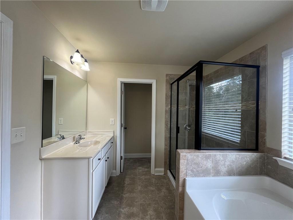 2299 Misty Ivy Court Buford, GA 30519 - Photo 18 of 26 a bathroom with a double vanity sink a mirror and a bathtub