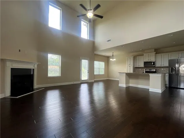 an empty room with wooden floor fireplace and windows
