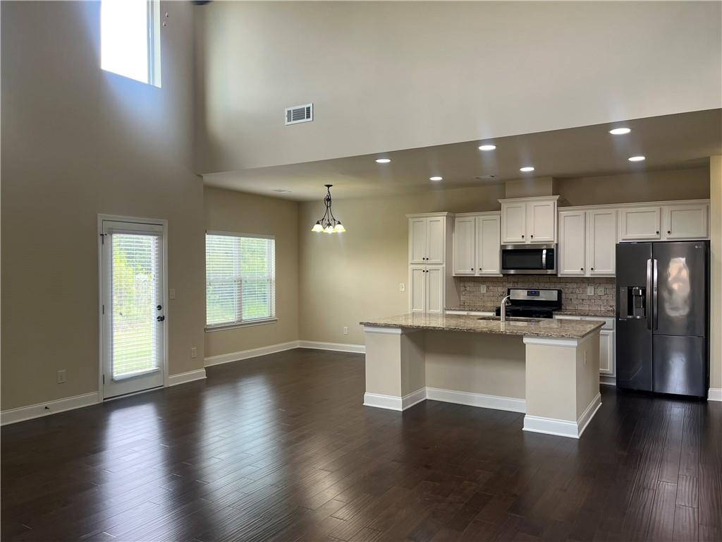 2299 Misty Ivy Court Buford, GA 30519 - Photo 7 of 26 an open kitchen with white cabinets wooden floor and stainless steel appliances