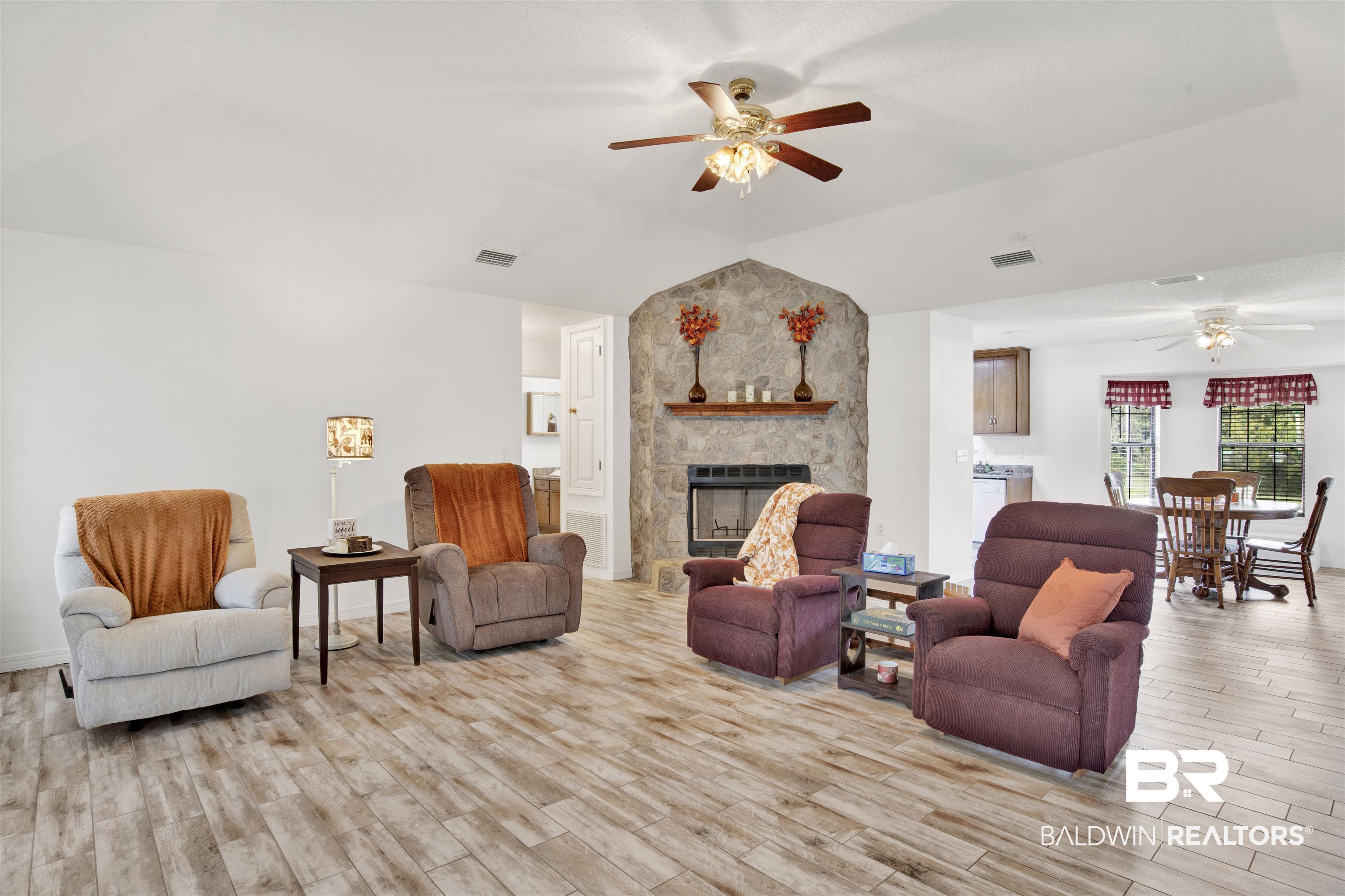54563 Splinter Hill Road Perdido, AL 36562 - Photo 11 of 29 Living room with lofted ceiling, ceiling fan, a stone fireplace, and light wood-type flooring
