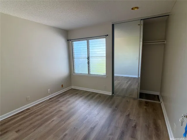 an empty room with wooden floor closet and windows