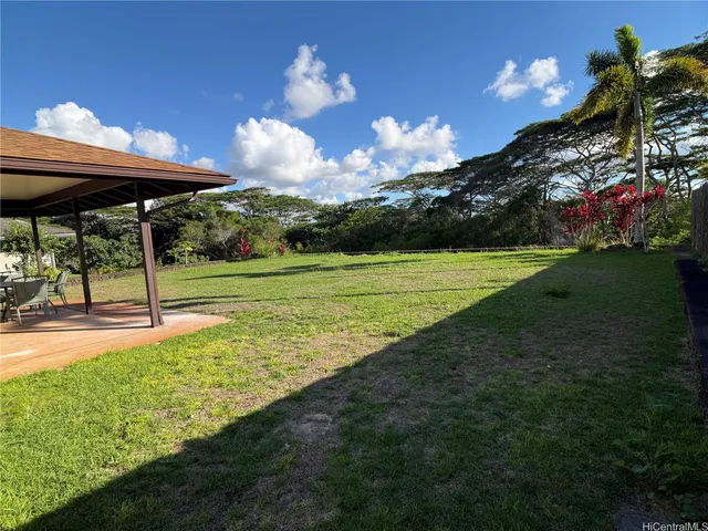 a view of a big yard with table and chairs under an umbrella
