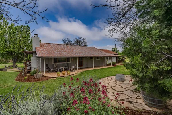 a view of a house with backyard garden and sitting area
