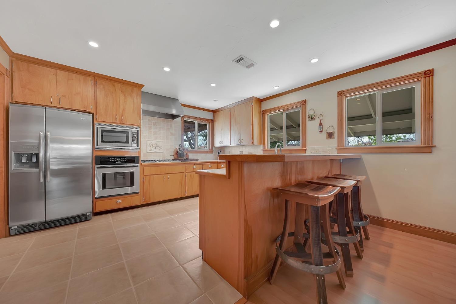 10801 Shenandoah Road Plymouth, CA 95669 - Photo 12 of 45 a kitchen with stainless steel appliances granite countertop a refrigerator a sink a stove and a dining table with wooden floor