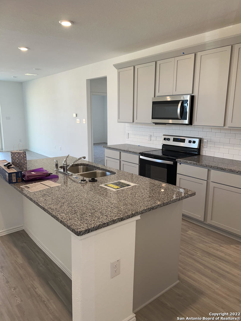 2164 Griffith Drive Seguin, TX 78155 - Photo 6 of 21 a kitchen with stainless steel appliances granite countertop a sink dishwasher a stove and a microwave oven with wooden floor