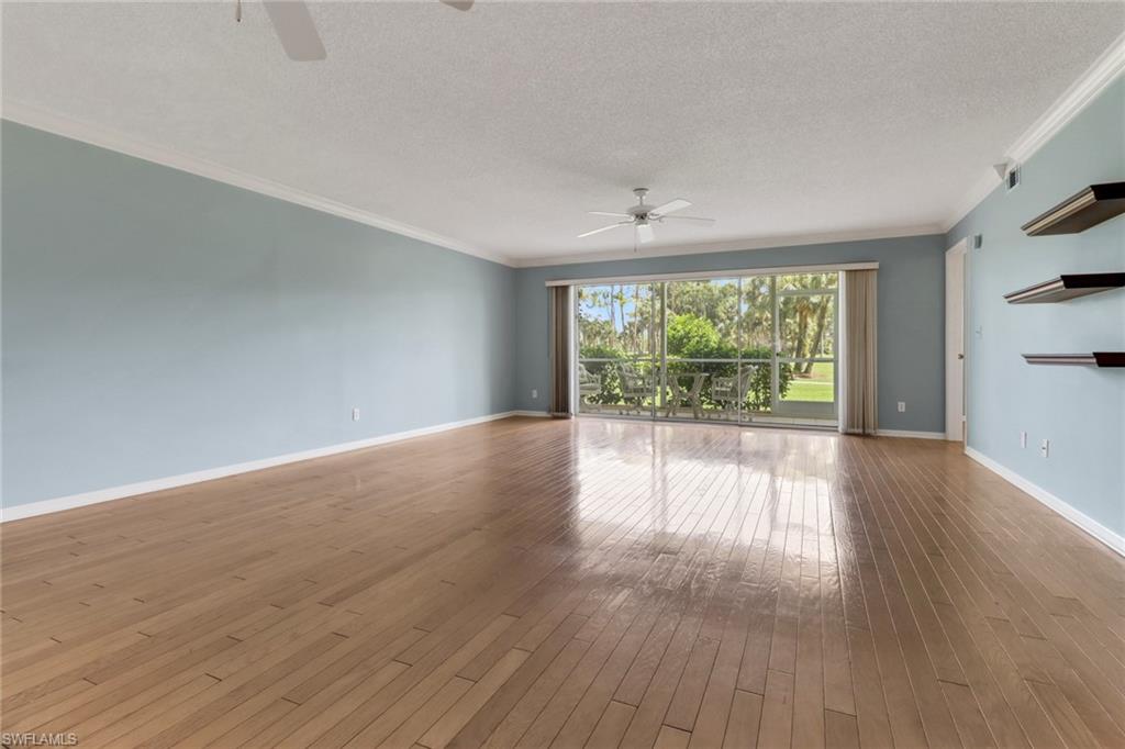 4556 Andover Way, Unit E106 Naples, FL 34112 - Photo 15 of 40 Empty room featuring ceiling fan, a textured ceiling, crown molding, and dark wood-type flooring