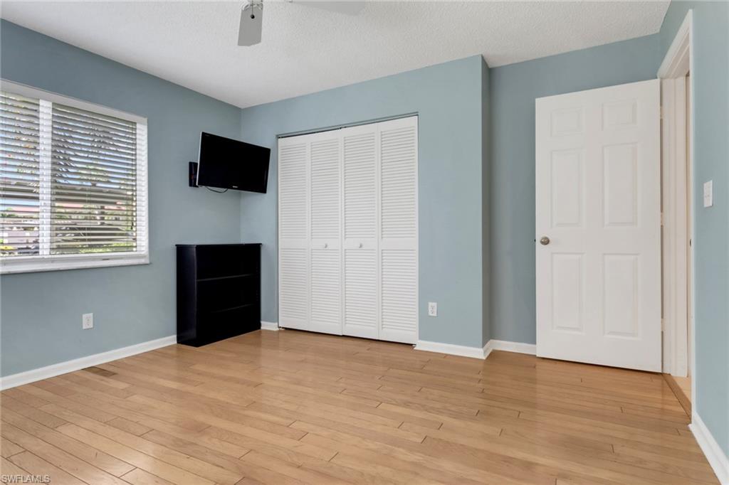 4556 Andover Way, Unit E106 Naples, FL 34112 - Photo 22 of 40 Unfurnished bedroom with a closet, light wood finished floors, ceiling fan, and a textured ceiling