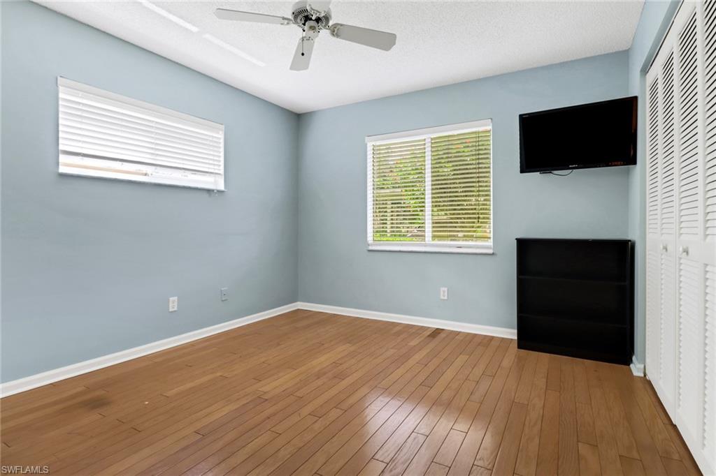 4556 Andover Way, Unit E106 Naples, FL 34112 - Photo 23 of 40 Unfurnished bedroom featuring a closet, hardwood / wood-style flooring, ceiling fan, and a textured ceiling