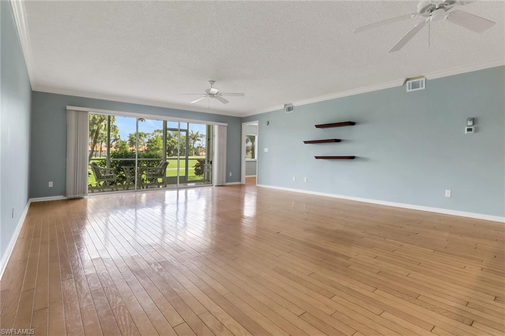 4556 Andover Way, Unit E106 Naples, FL 34112 - Photo 8 of 40 Unfurnished living room featuring ceiling fan, a textured ceiling, ornamental molding, and light wood-style floors