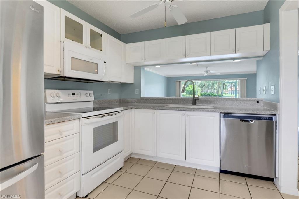4556 Andover Way, Unit E106 Naples, FL 34112 - Photo 10 of 40 Kitchen featuring ceiling fan, stainless steel appliances, white cabinetry, and glass insert cabinets