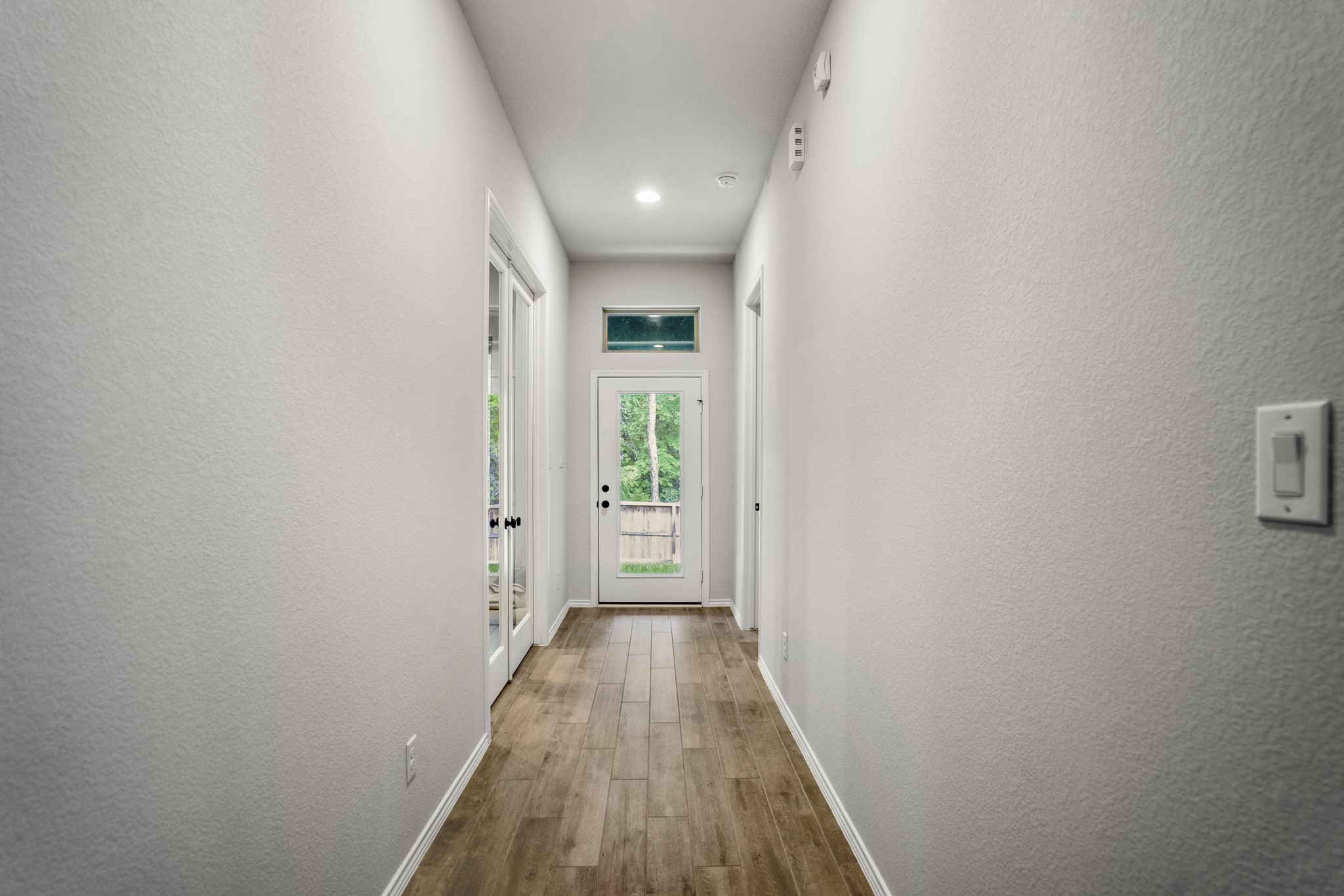 334 Topper Pines Drive Montgomery, TX 77316 - Photo 17 of 49 Turning into the hallway, the study sits behind French doors on the left, the primary suite is on the right, and the back door straight ahead leads out toward the covered patio and greenbelt.