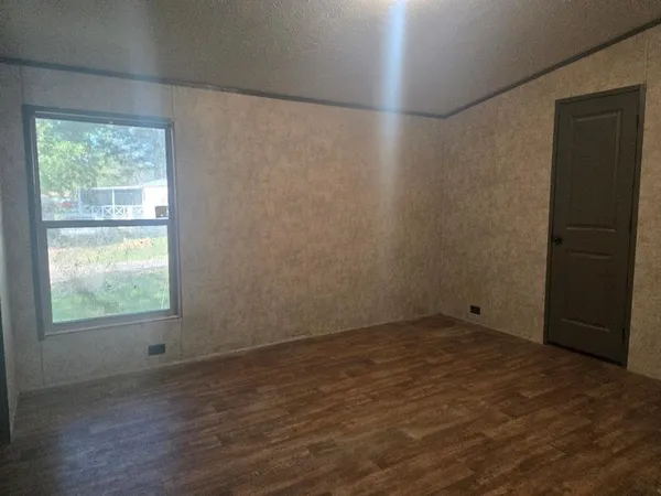 a view of an empty room with wooden floor and a bathroom