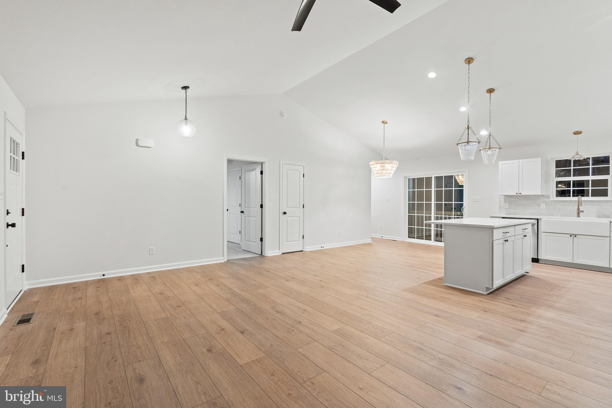1080 Eastham Road Bumpass, VA 23024 - Photo 6 of 43 a large white kitchen with kitchen island a sink wooden floor and white cabinets