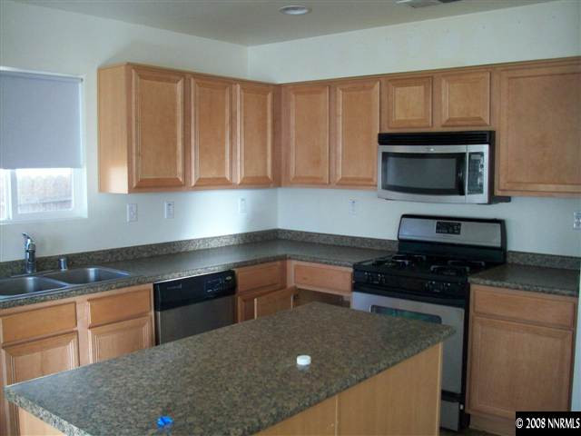 9275 Red Baron Boulevard Reno, NV 89506 - Photo 7 of 9 a kitchen with granite countertop a stove top oven a sink dishwasher and white cabinets with wooden floor