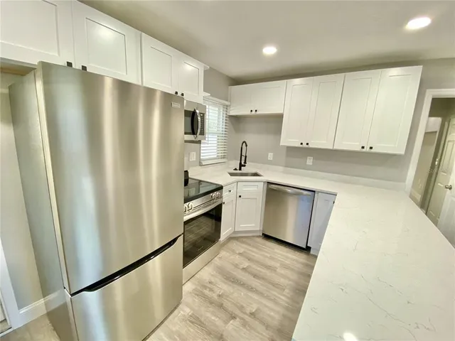 a kitchen with stainless steel appliances a refrigerator a sink and white cabinets