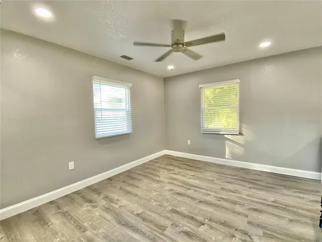 an empty room with windows and fan