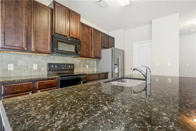 a kitchen with stainless steel appliances granite countertop a stove a sink and a microwave