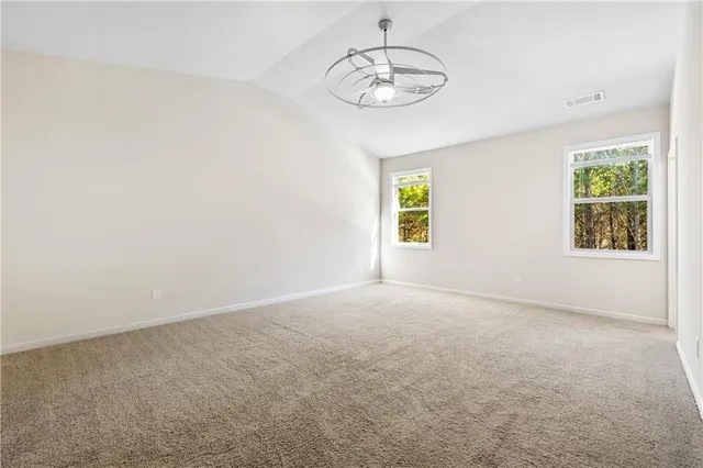 an empty room with windows and chandelier fan