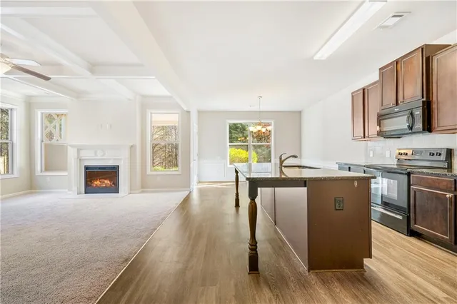a living room with stainless steel appliances granite countertop furniture wooden floor and a fireplace