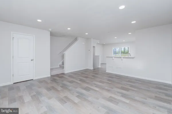 a view of an empty room with wooden floor and windows