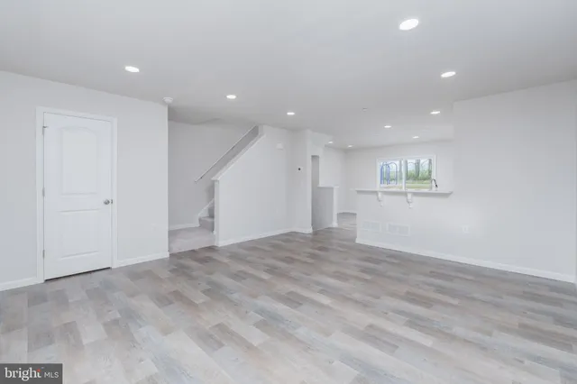 a view of an empty room with wooden floor and windows