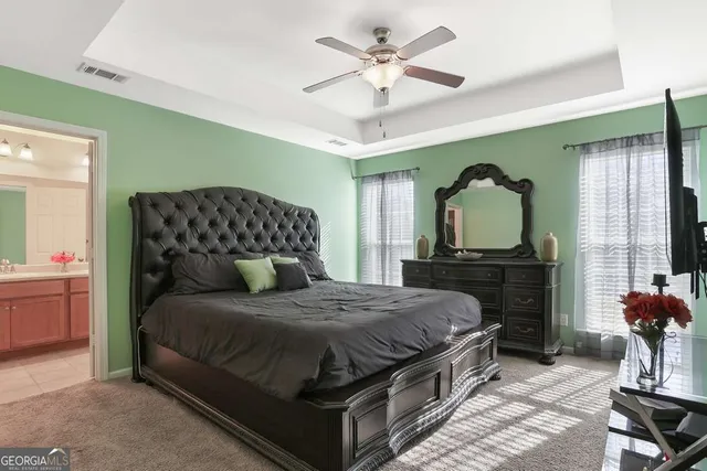 a bedroom with a bed a chandelier with dresser and mirror