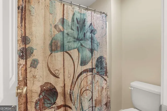 a bathroom with a toilet sink and shower curtain