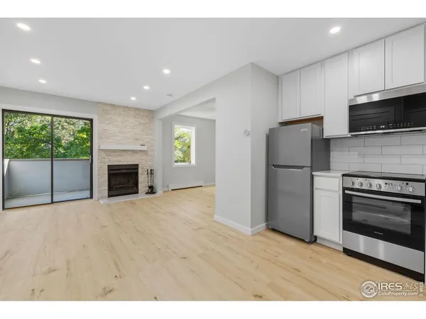 a view of kitchen with stainless steel appliances wooden floor and window