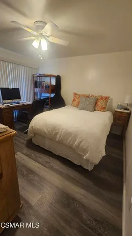 a bedroom with a bed and dresser with wooden floor