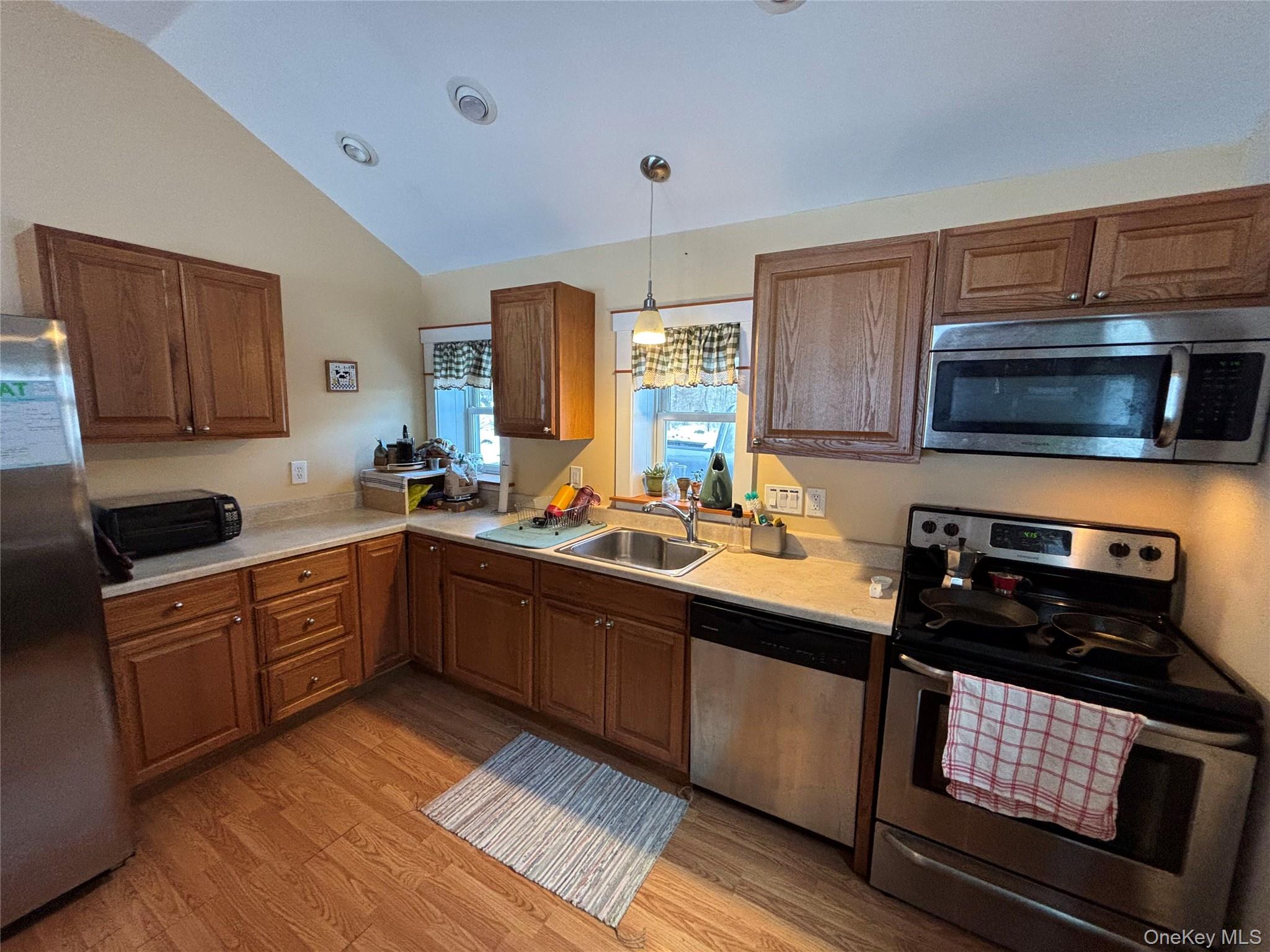 273 South Road Holmes, NY 12531 - Photo 10 of 13 Kitchen featuring stainless steel appliances, light countertops, lofted ceiling, light wood-style floors, and hanging light fixtures