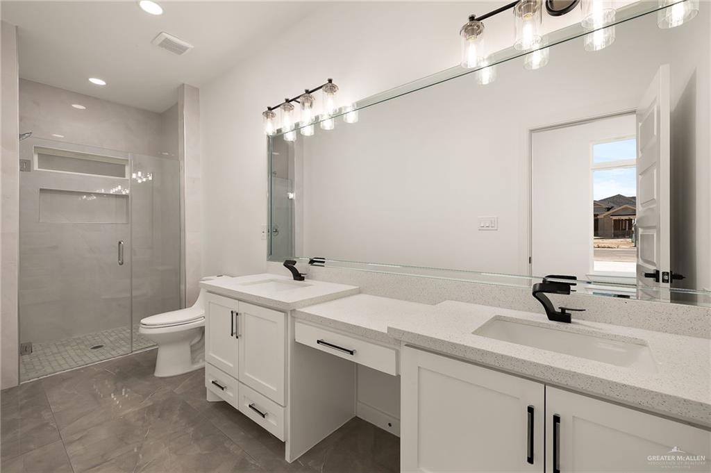 422 Reef Road Donna, TX 78537 - Photo 11 of 17 Bathroom featuring a double vanity with white cabinetry, quartz countertops, and matte black fixtures