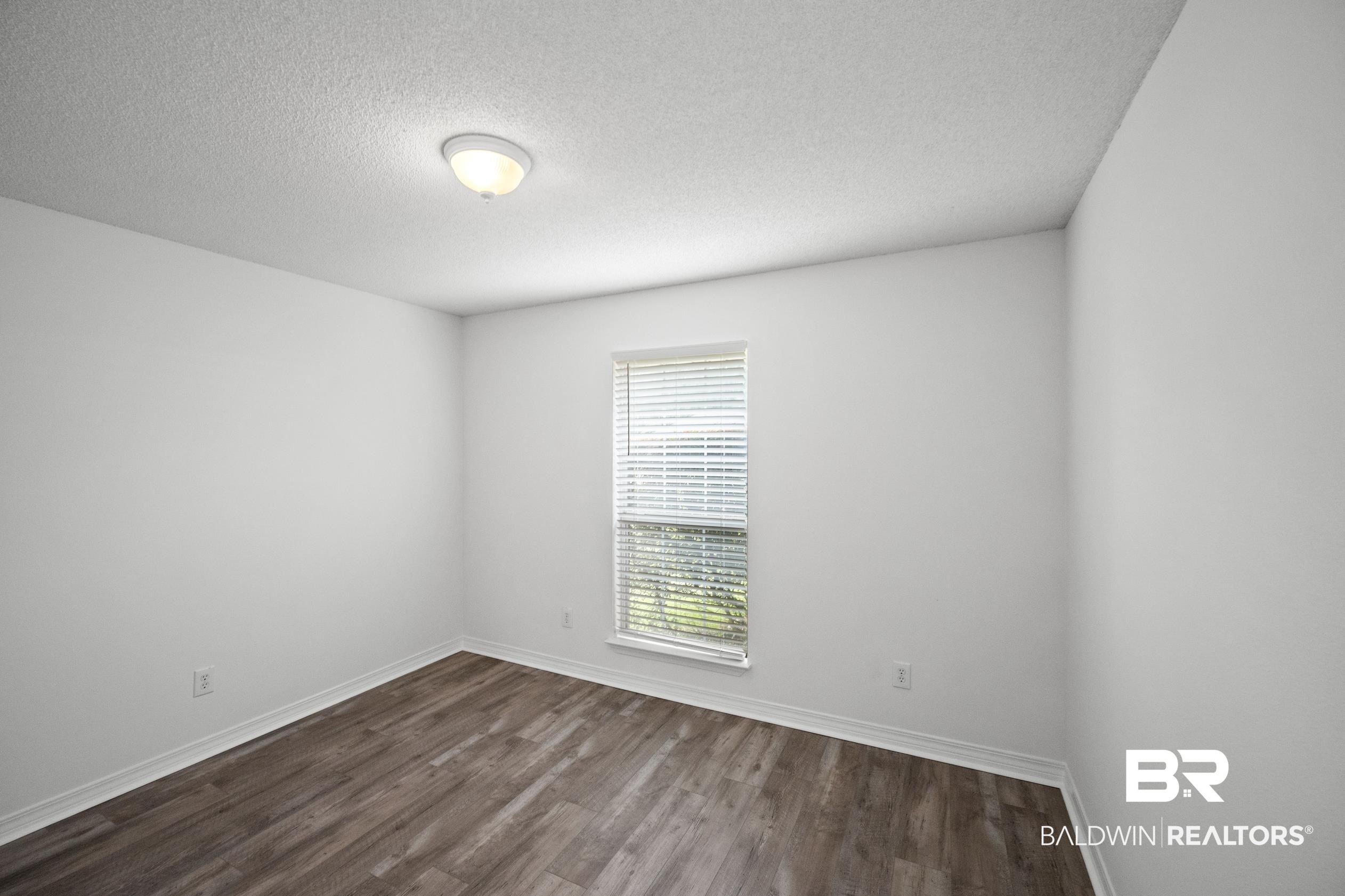 306 Monteith Oaks Drive Foley, AL 36535 - Photo 23 of 38 Empty room with dark wood finished floors and a textured ceiling