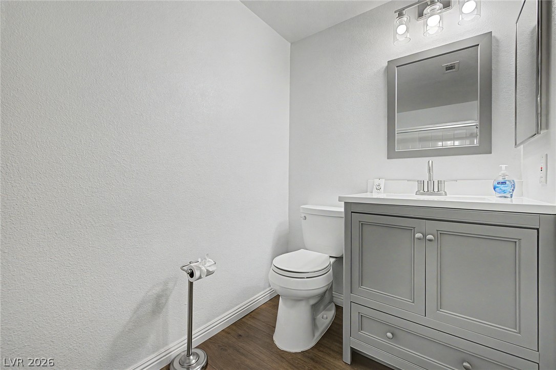 2153 Quarry Ridge Street, Unit 103 Las Vegas, NV 89117 - Photo 28 of 42 A refined bathroom features a modern gray vanity, sleek white toilet, and polished wood-look flooring.