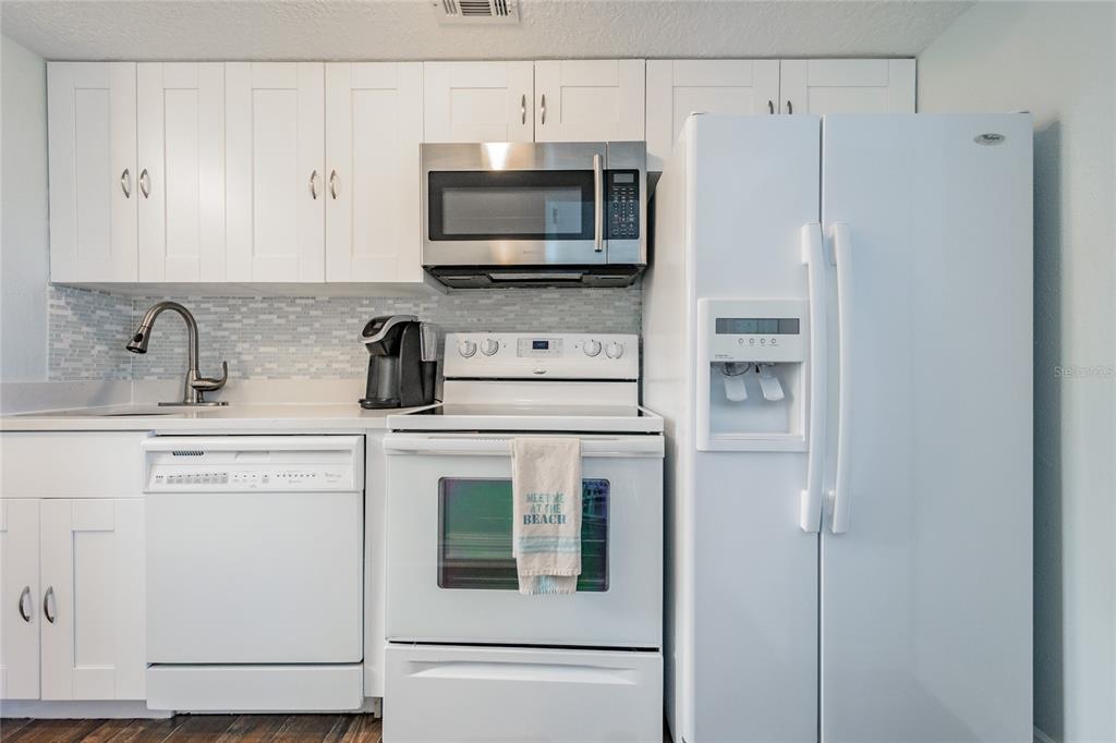 2570 Gary Circle, Unit 4 Dunedin, FL 34698 - Photo 7 of 20 a kitchen with stainless steel appliances white cabinets and a refrigerator